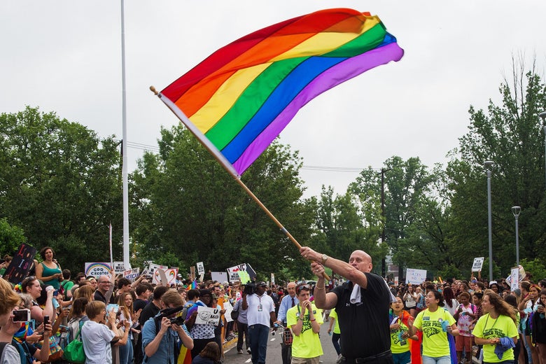 Principal Pete Cahall, waves a rainbow flag, symbolizing gay pride, at a rally of about 1000 Woodrow Wilson High School students and gay supporters June 9, 2014 at Woodrow Wilson High School in Washington, DC. The rally was held to counter a planned protest by Westboro Baptist Church, the Kansas-based organization known for anti-gay picketing at funerals. AFP PHOTO/Paul J. Richards (Photo credit should read PAUL J. RICHARDS/AFP/Getty Images)